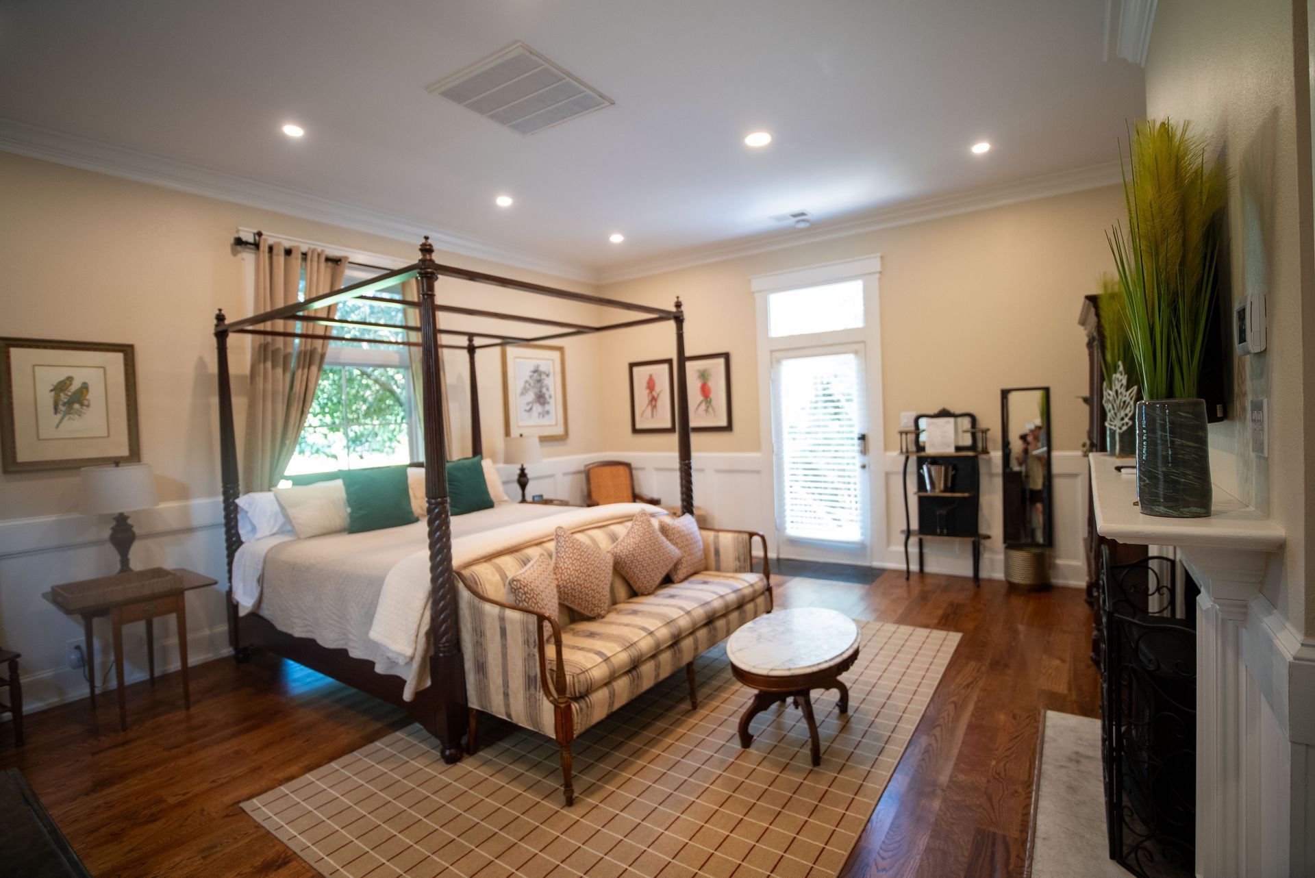 a bedroom with a canopy bed , couch , table and fireplace .