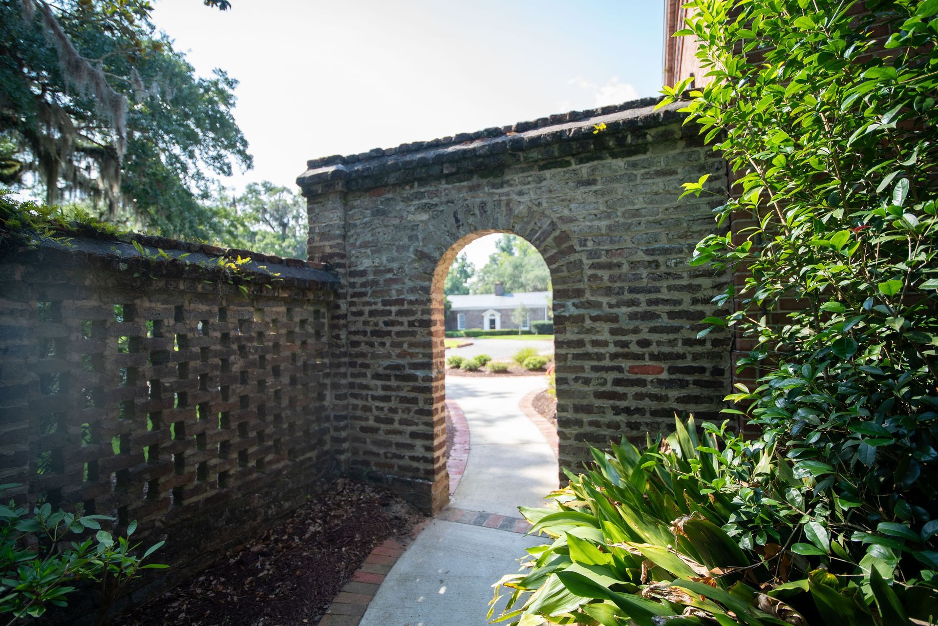 a brick wall with an archway leading to a garden .