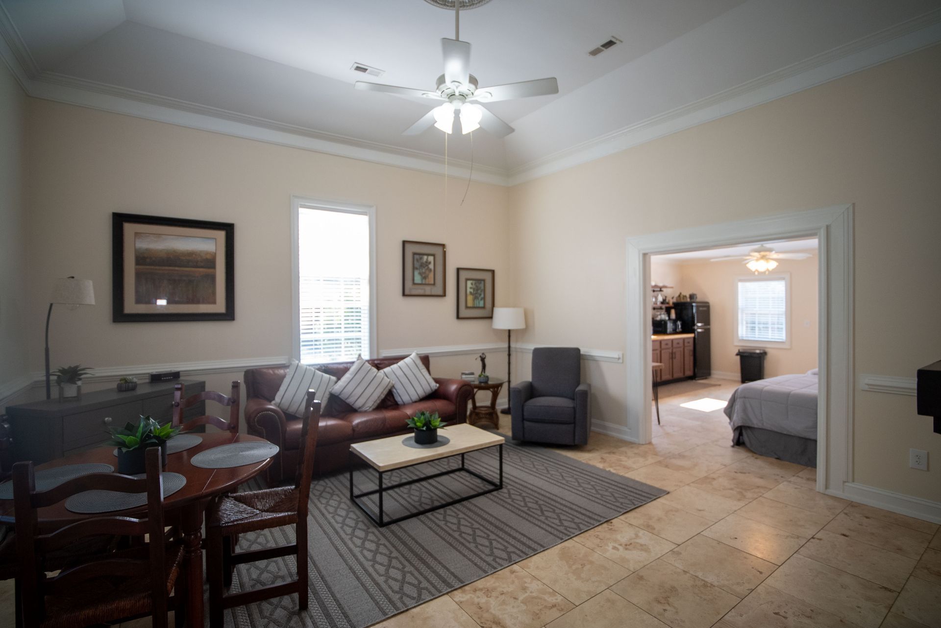 a living room with a couch , chairs , a table and a ceiling fan .