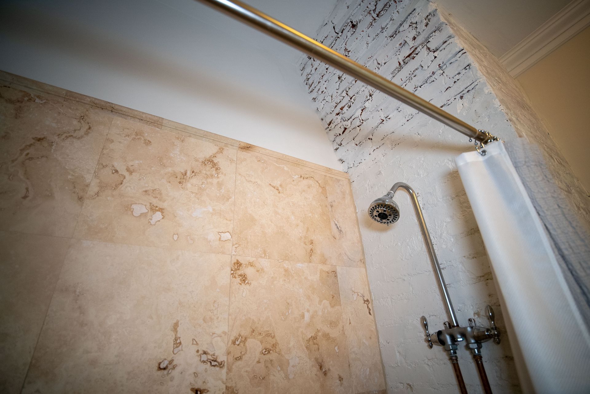 a shower with a shower head and a shower curtain hanging from the ceiling .