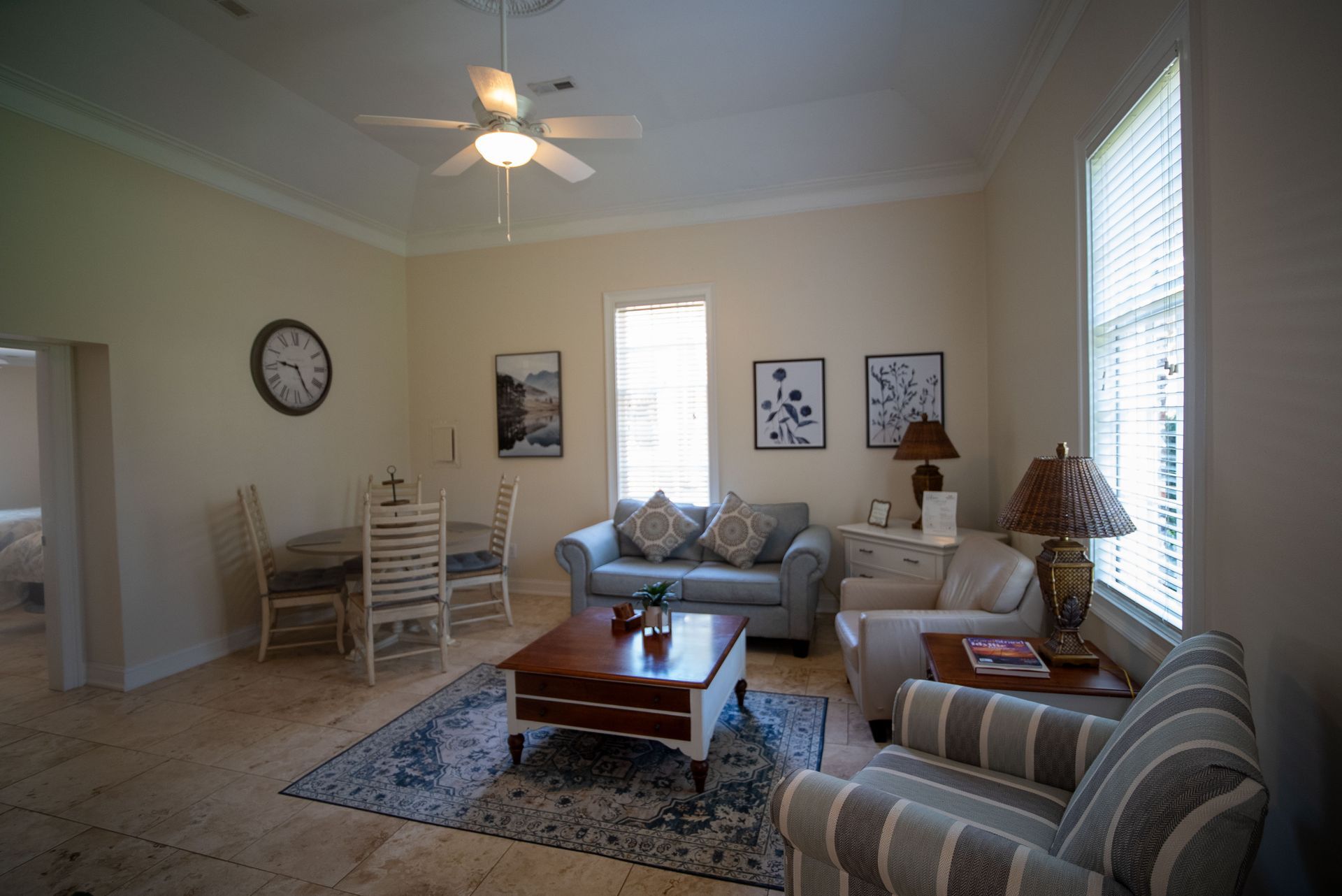 a living room with a couch , chairs , coffee table and a ceiling fan .