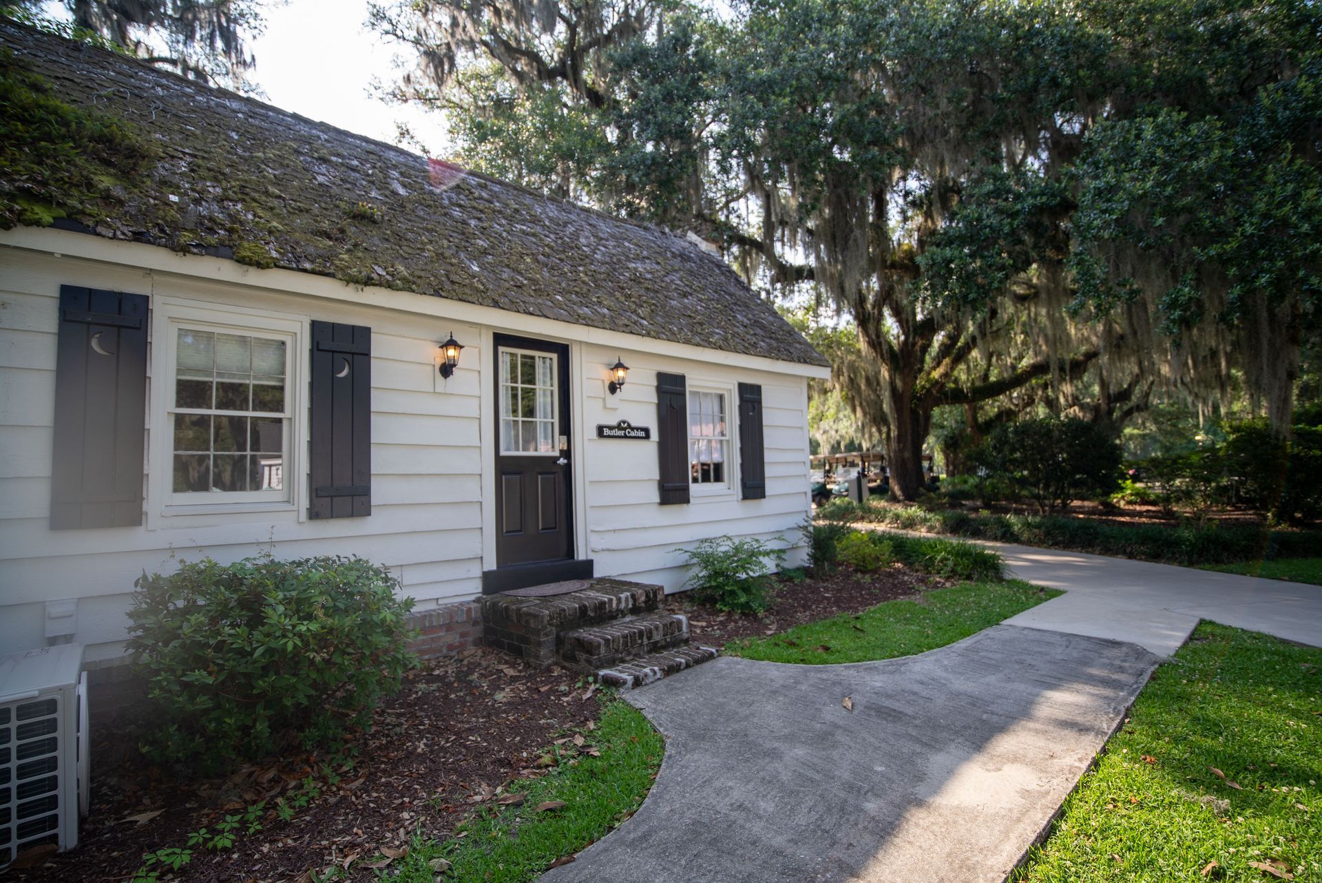 a small white house with black shutters and a walkway leading to it .