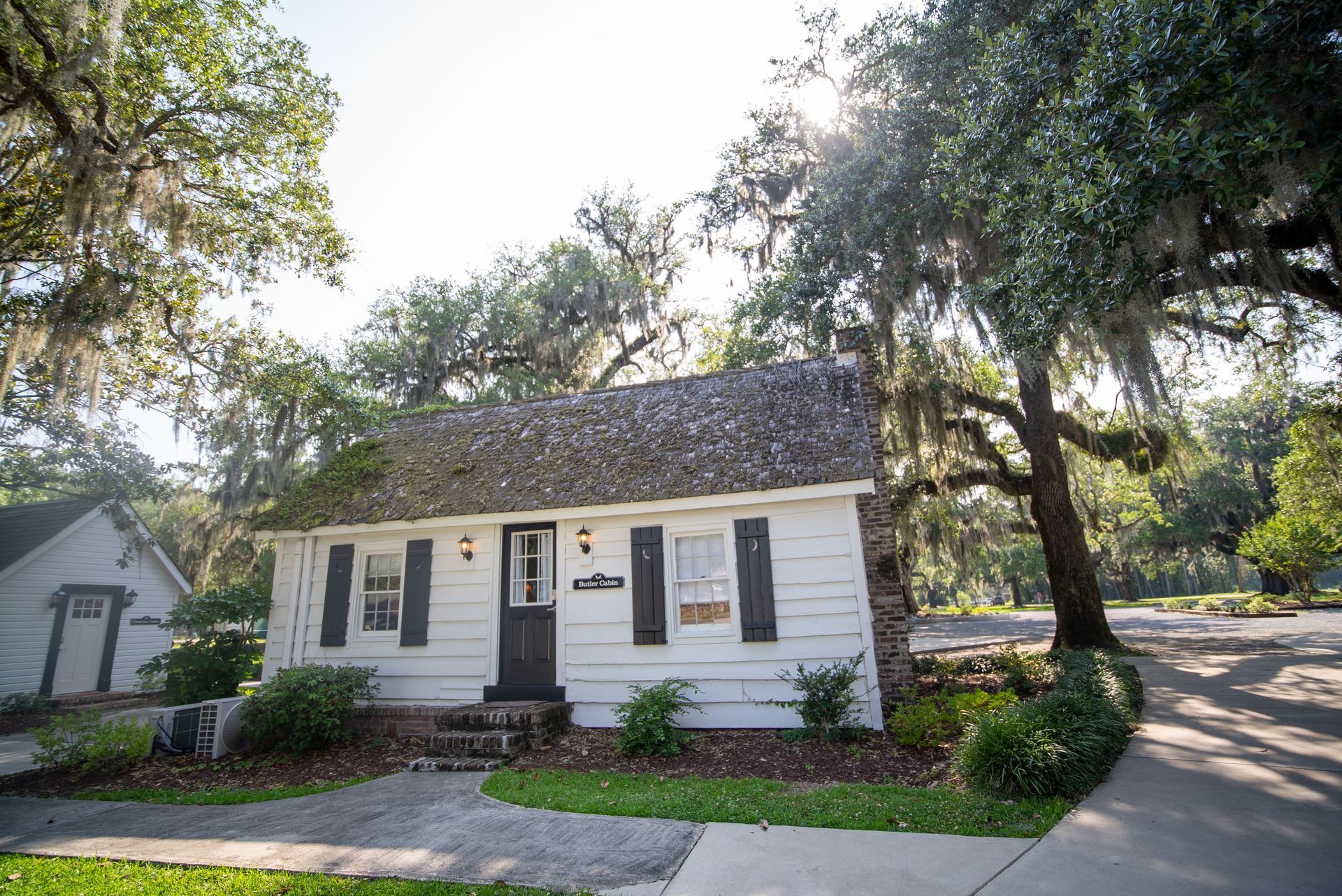 a small white house with black shutters is surrounded by trees .