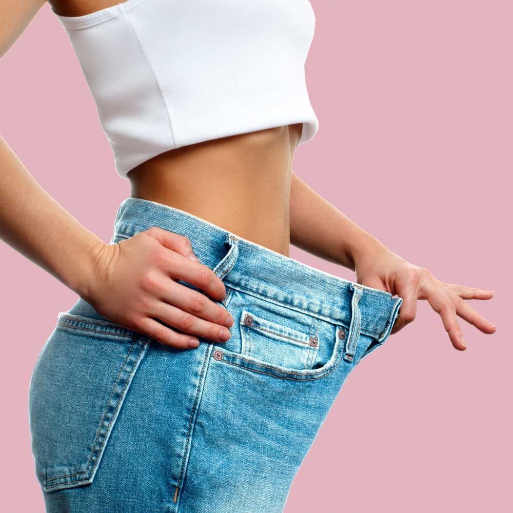 A woman is wearing a white crop top and blue jeans.