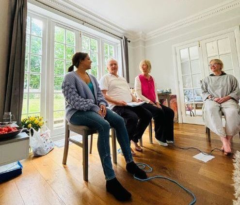 A group of people are sitting in chairs in a living room.