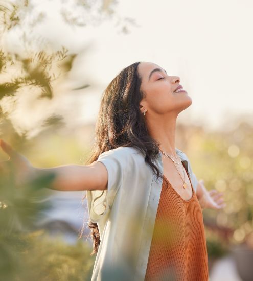 A woman is standing in a field with her arms outstretched.