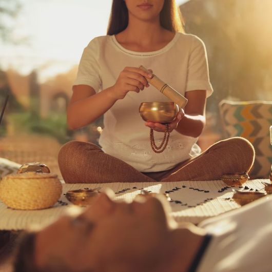 A woman is sitting in a lotus position holding a bowl