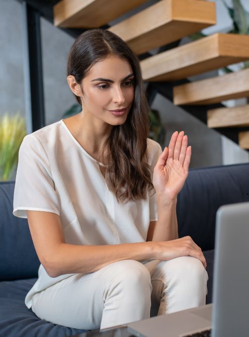 A woman is sitting on a couch using a laptop computer