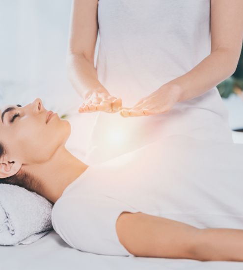 A woman is laying on a bed getting a healing session.