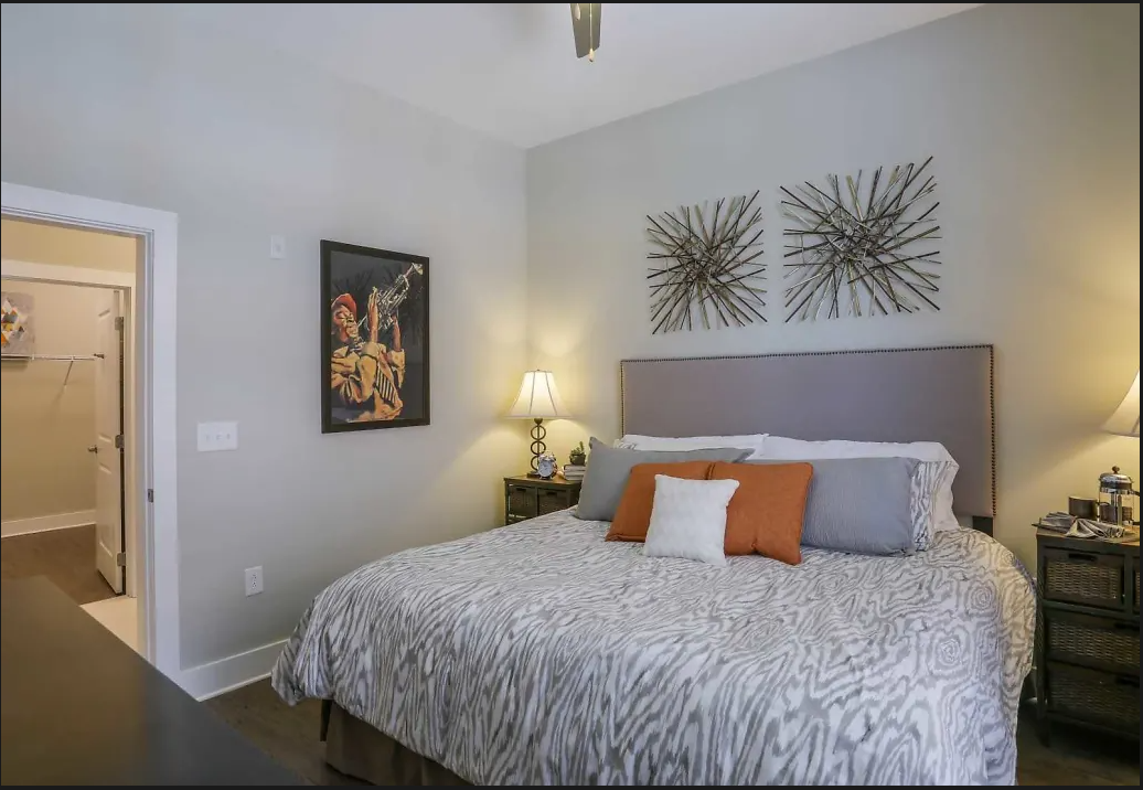 Bedroom with a king-size bed, gray headboard, zebra-pattern bedding, and two lamps on nightstands.