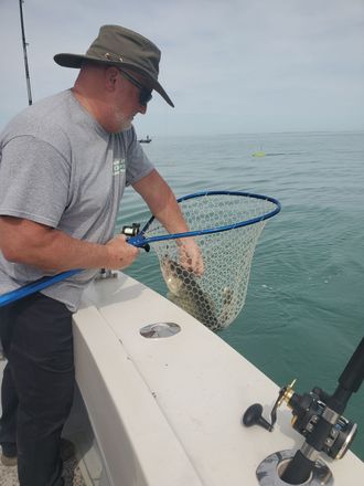 A man is catching a fish in a net on a boat.