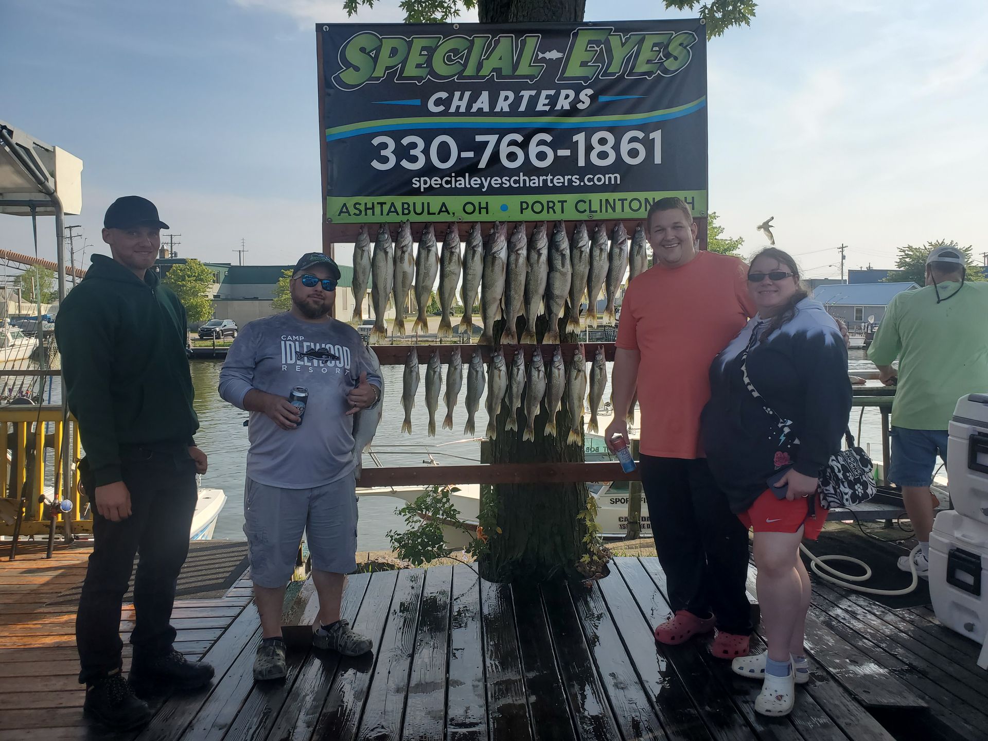 A group of people standing on a dock in front of a sign for special eyes charters