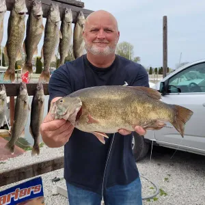 A man is holding a large fish in front of a sign that says arthurs