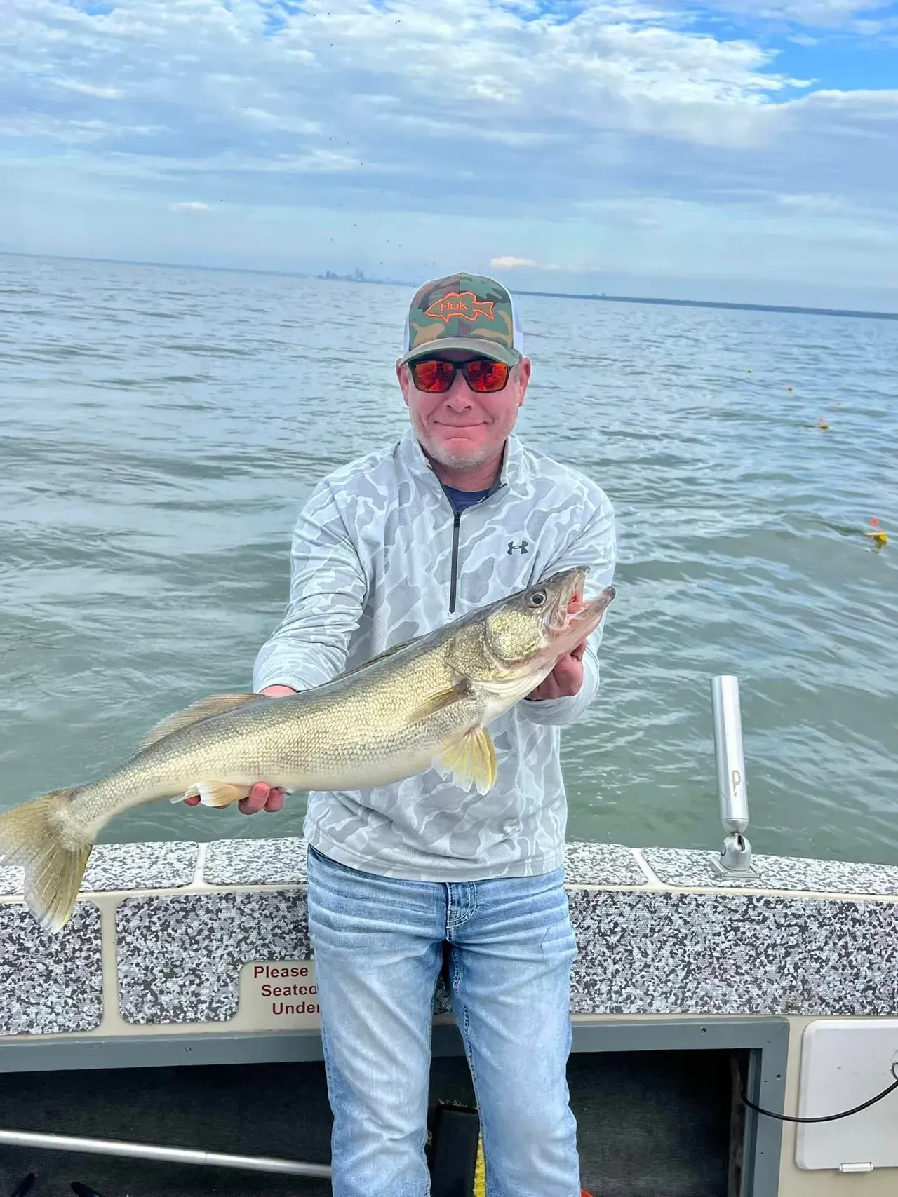 A man is standing on a boat holding a large fish.