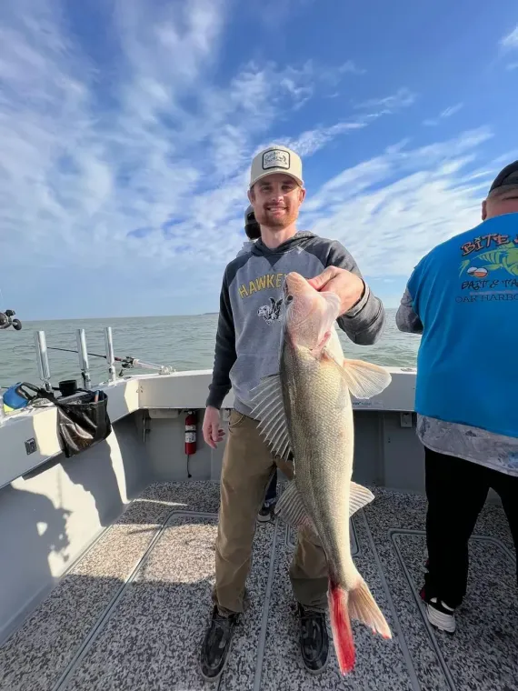 A man is holding a large fish on a boat.