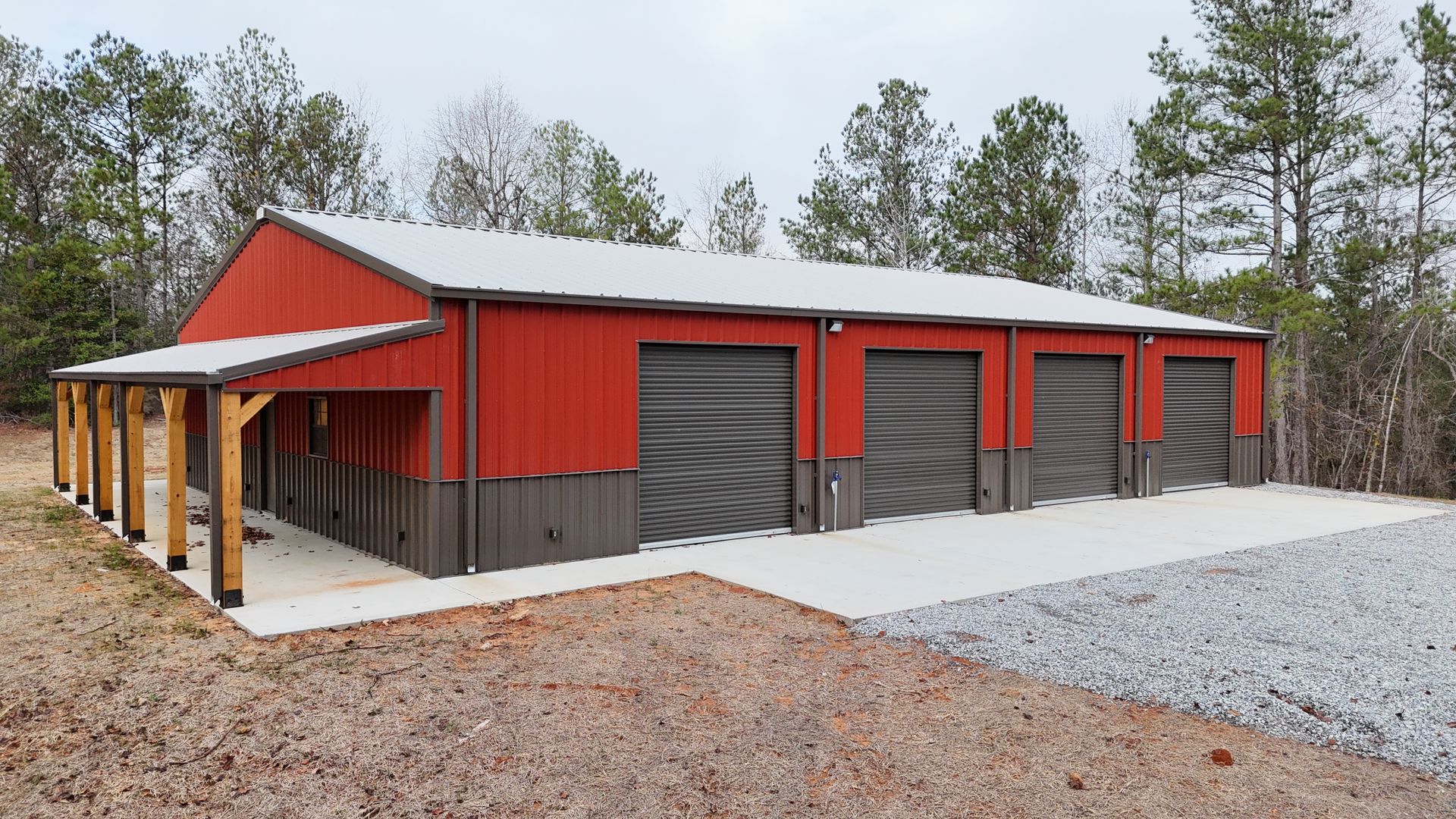 An aerial view of a red barn with a white roof and a driveway surrounded by trees.