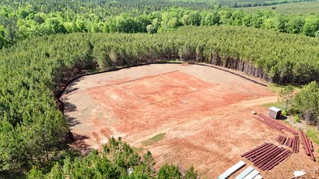 An aerial view of a dirt field surrounded by trees.