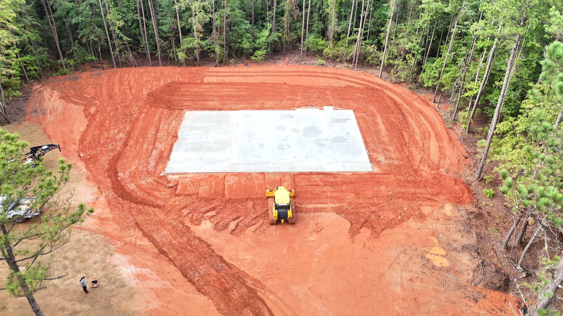 An aerial view of a bulldozer moving dirt in a field.