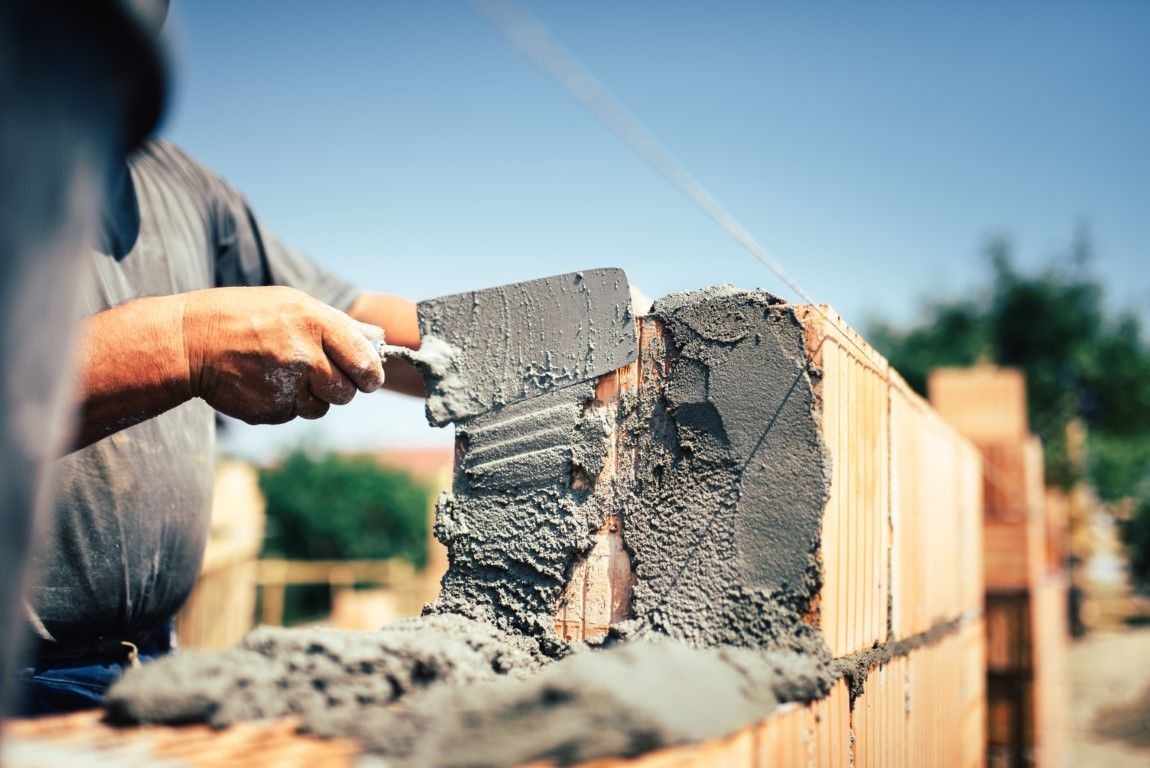 Worker applying mortar to a brick wall outdoors