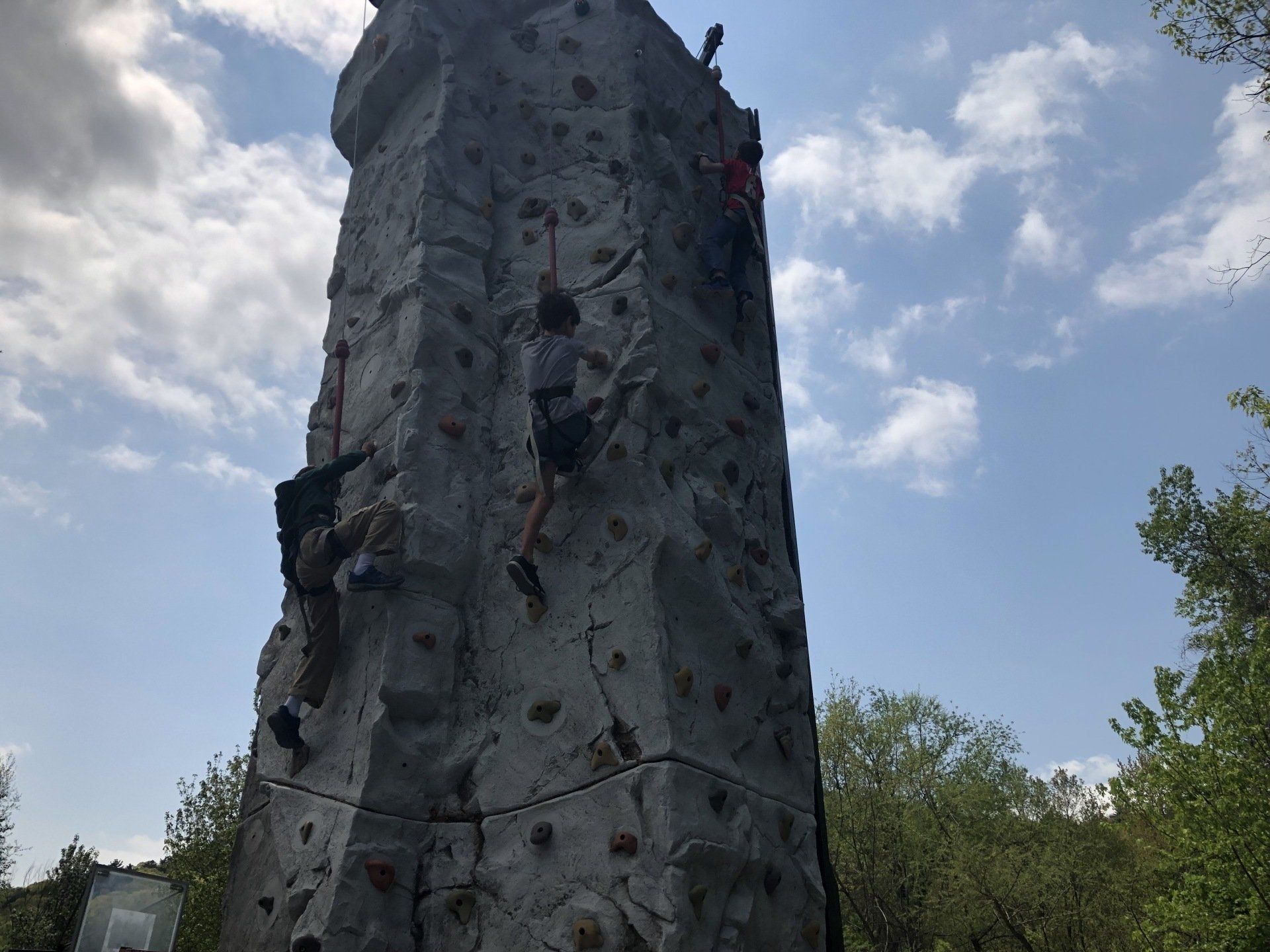Children Climb Against the Blue Sky Background — Chicopee, MA — Cliffhangers Portable Rock Climbing Wall