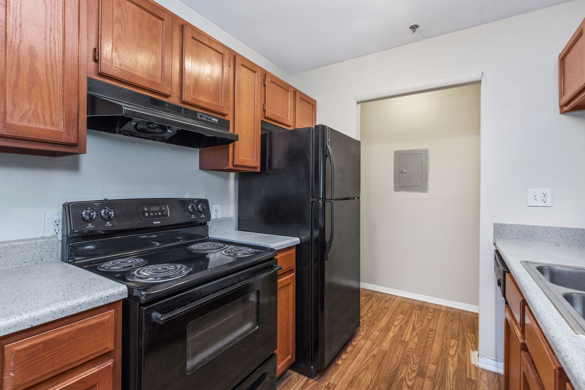 A kitchen with wooden cabinets, a black stove and refrigerator, and grey countertops.