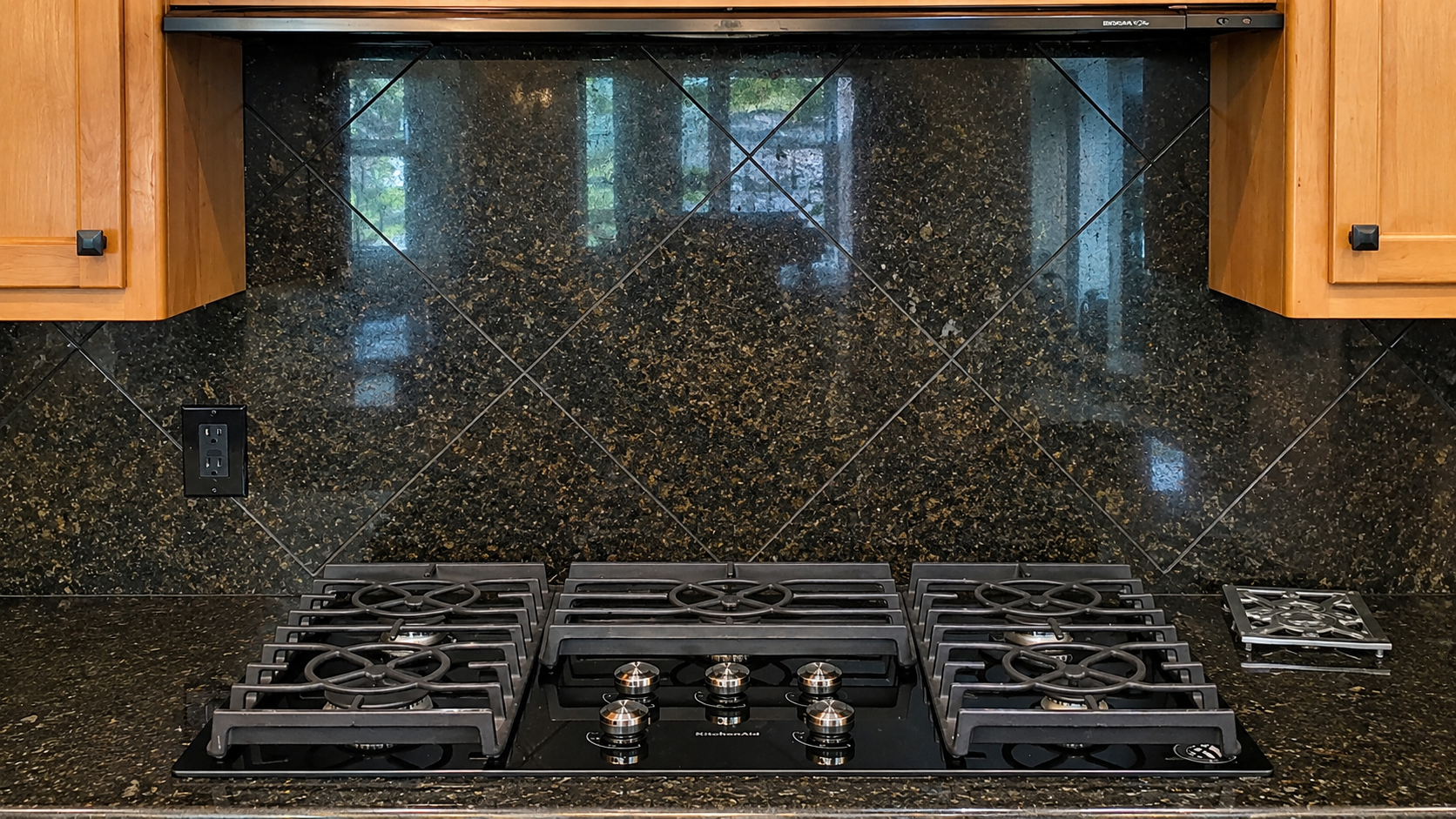 White kitchen with island, black granite countertop, stainless steel appliances, and wooden bar stools.