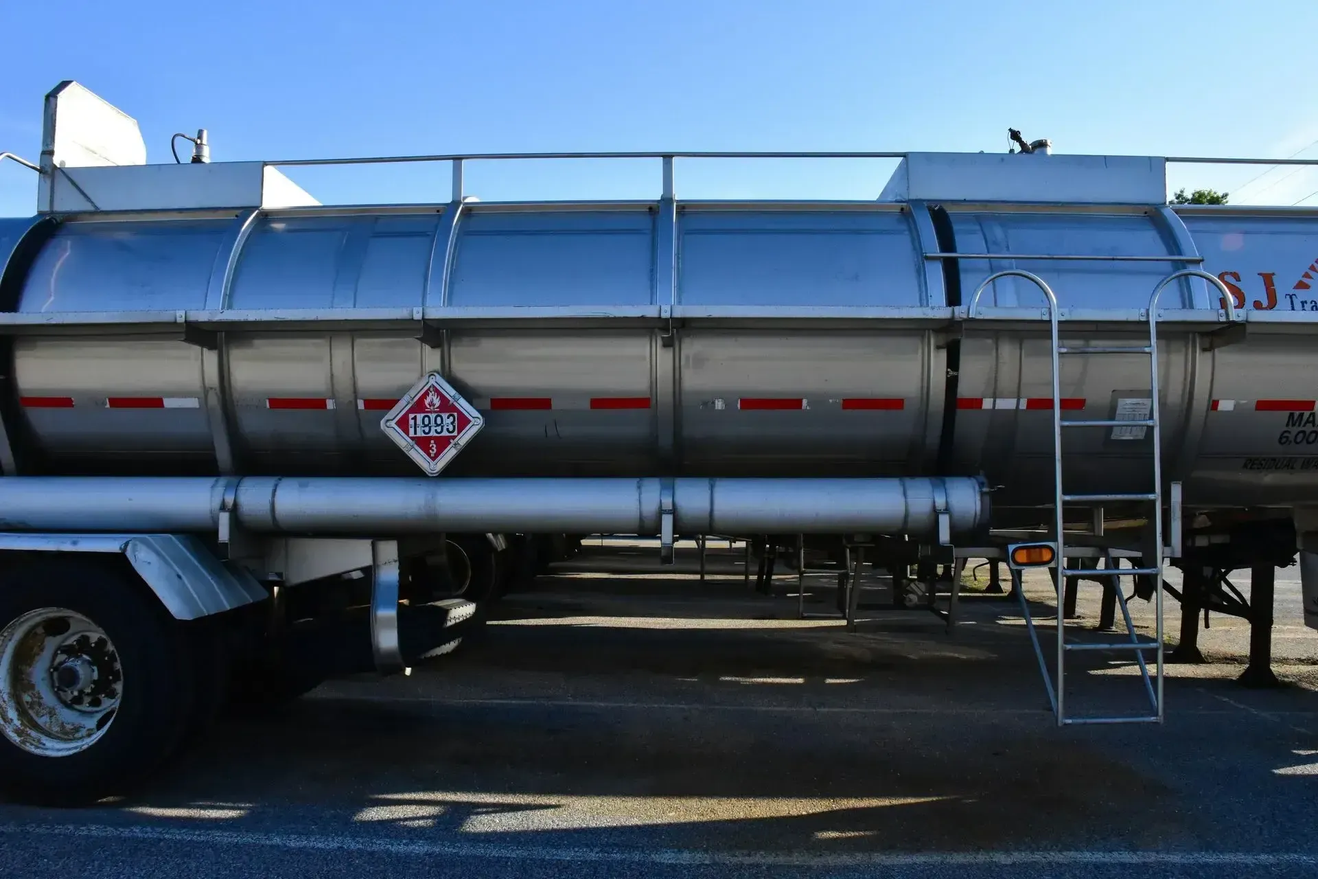 A stainless steel tanker truck with a ladder attached to it
