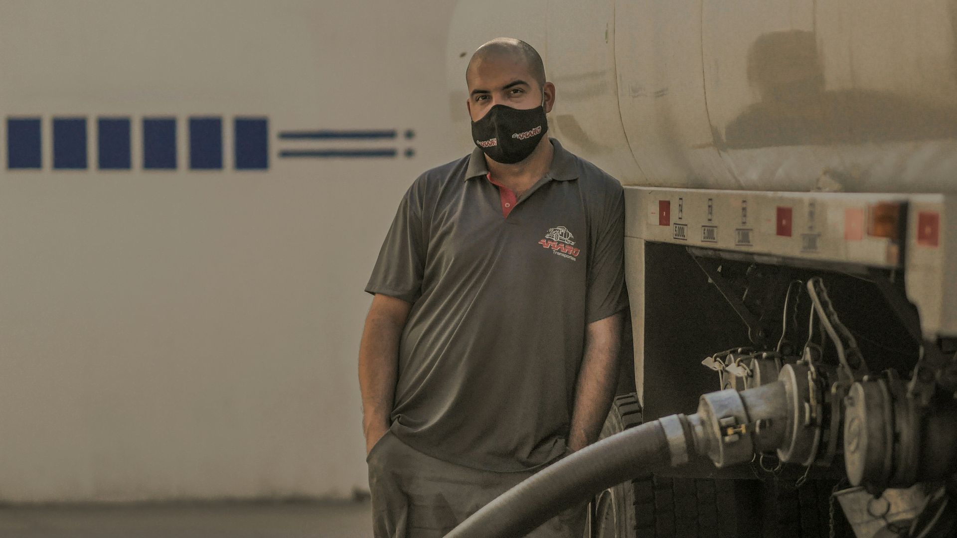 A man wearing a mask is standing next to a truck.