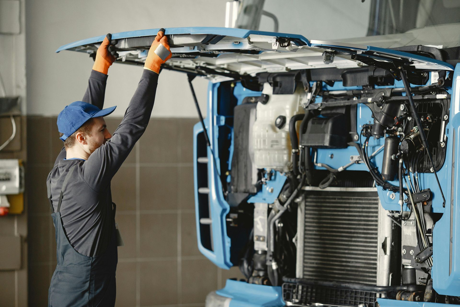 A man is working on the hood of a truck in a garage.