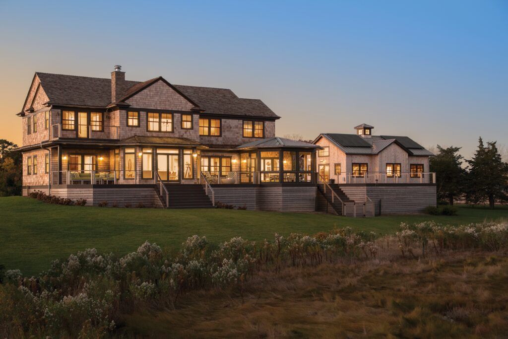 A large house is sitting on top of a lush green field.