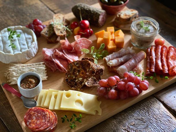 A wooden cutting board topped with a variety of meats and cheeses.