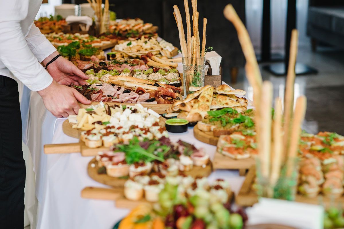 A man is standing in front of a buffet table filled with food.