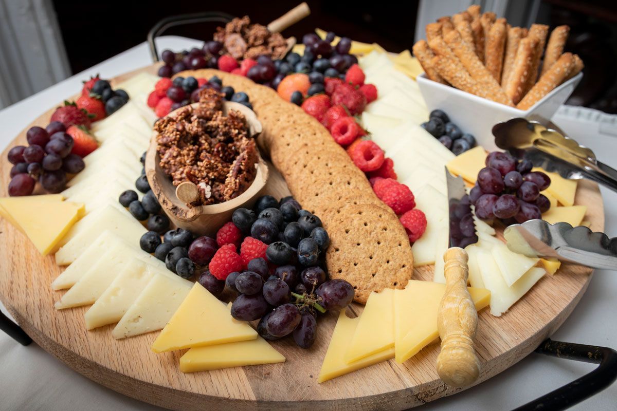 A wooden cutting board filled with cheese , fruit and crackers.