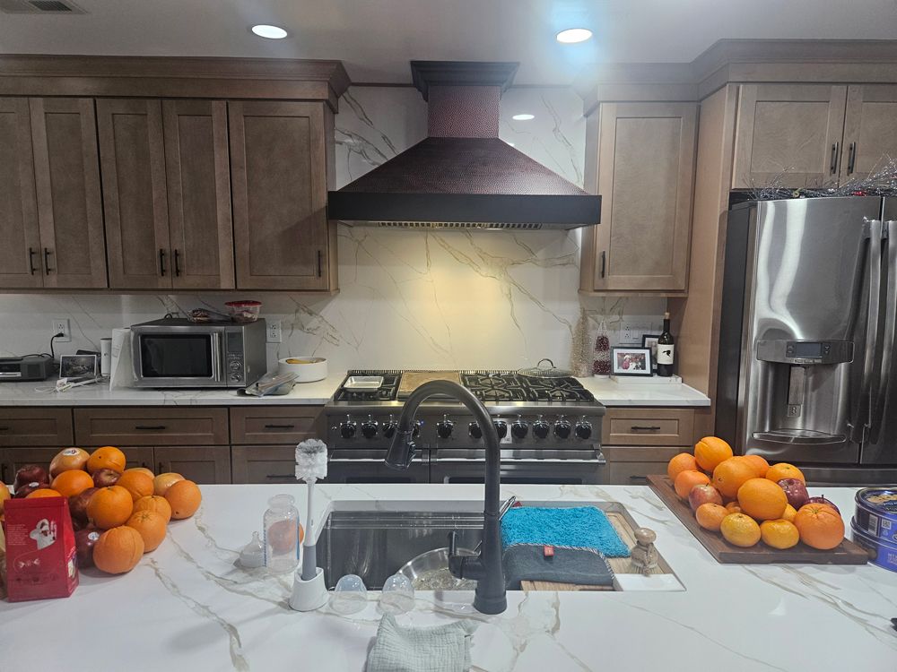 A kitchen with stainless steel appliances , wooden cabinets , a sink , stove and refrigerator.