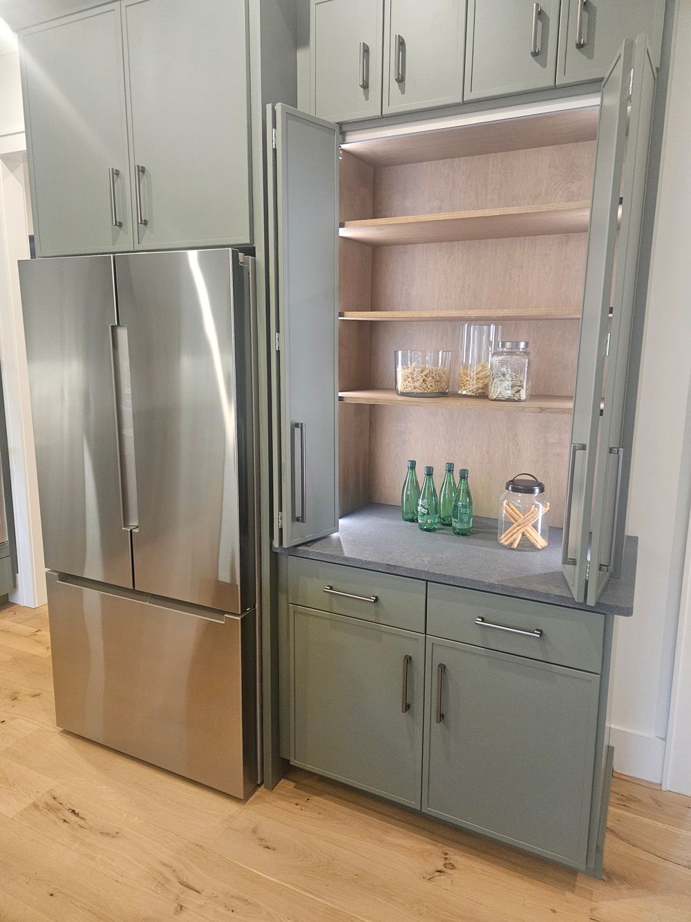 A kitchen with stainless steel appliances and gray cabinets.