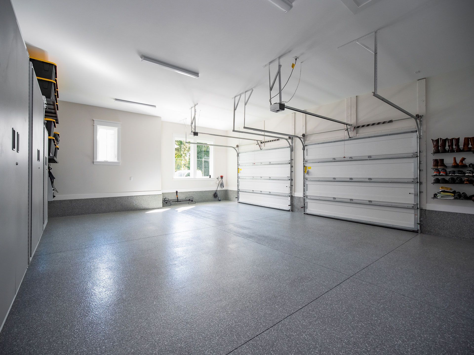 Empty, modern garage with gray epoxy floor and closed white garage doors.