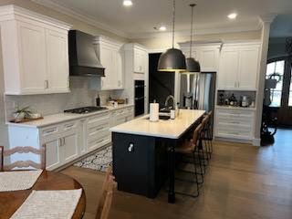 A kitchen with white cabinets and a black island.