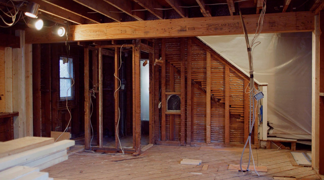 A room that is being remodeled with a staircase in the corner.