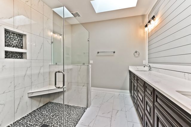 A bathroom with a walk in shower and a skylight