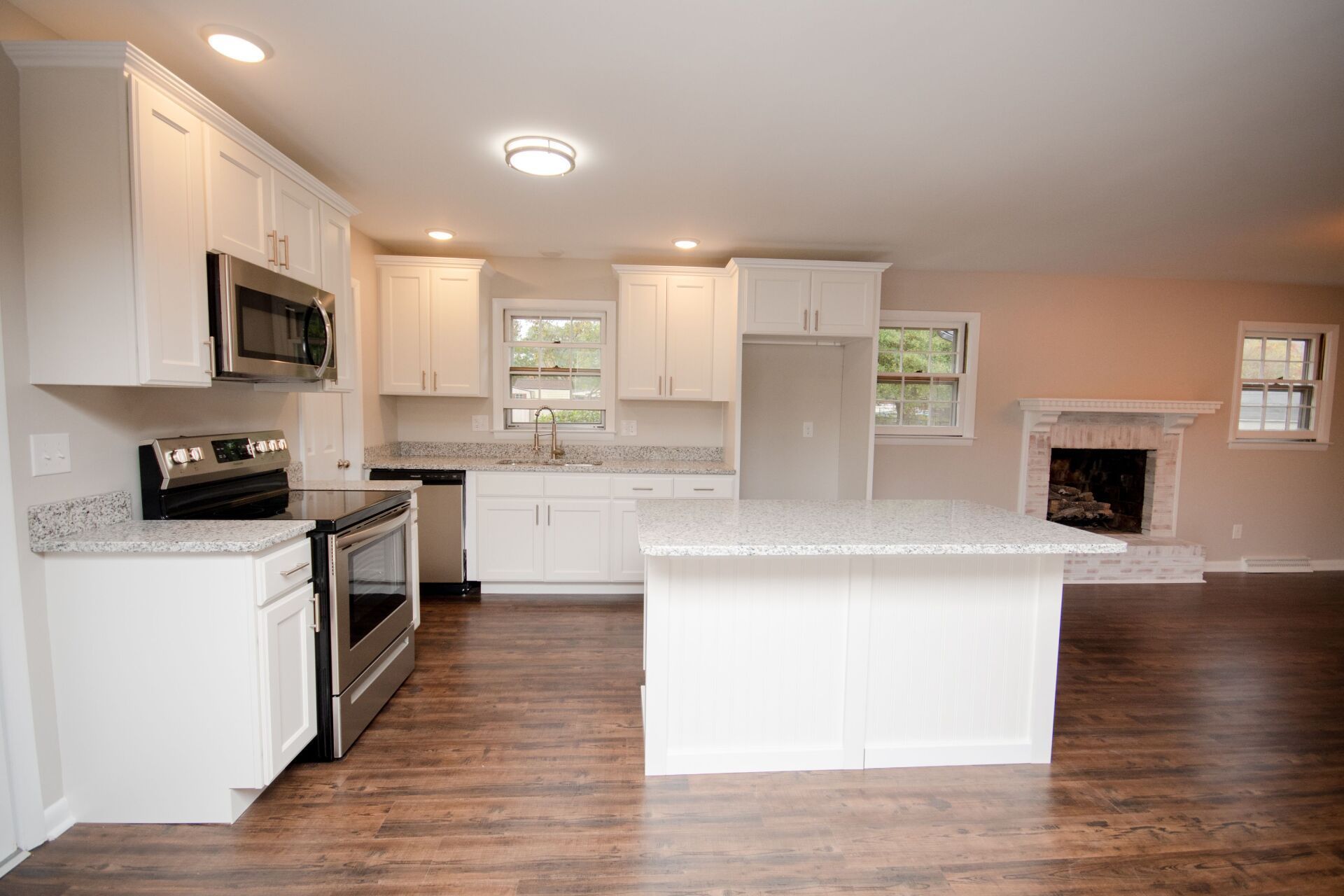 Man installing wood-look flooring indoors; stacked planks in foreground, walls in background.