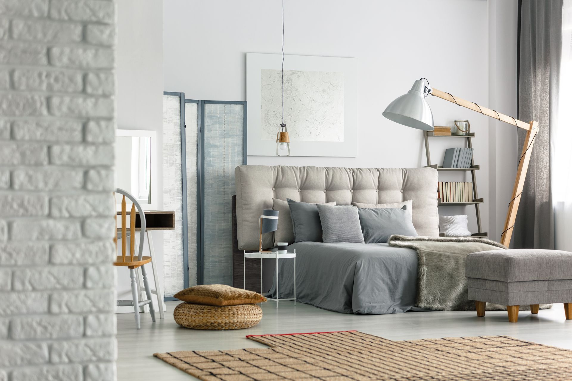 A bedroom with a bed , ottoman , lamp and rug.