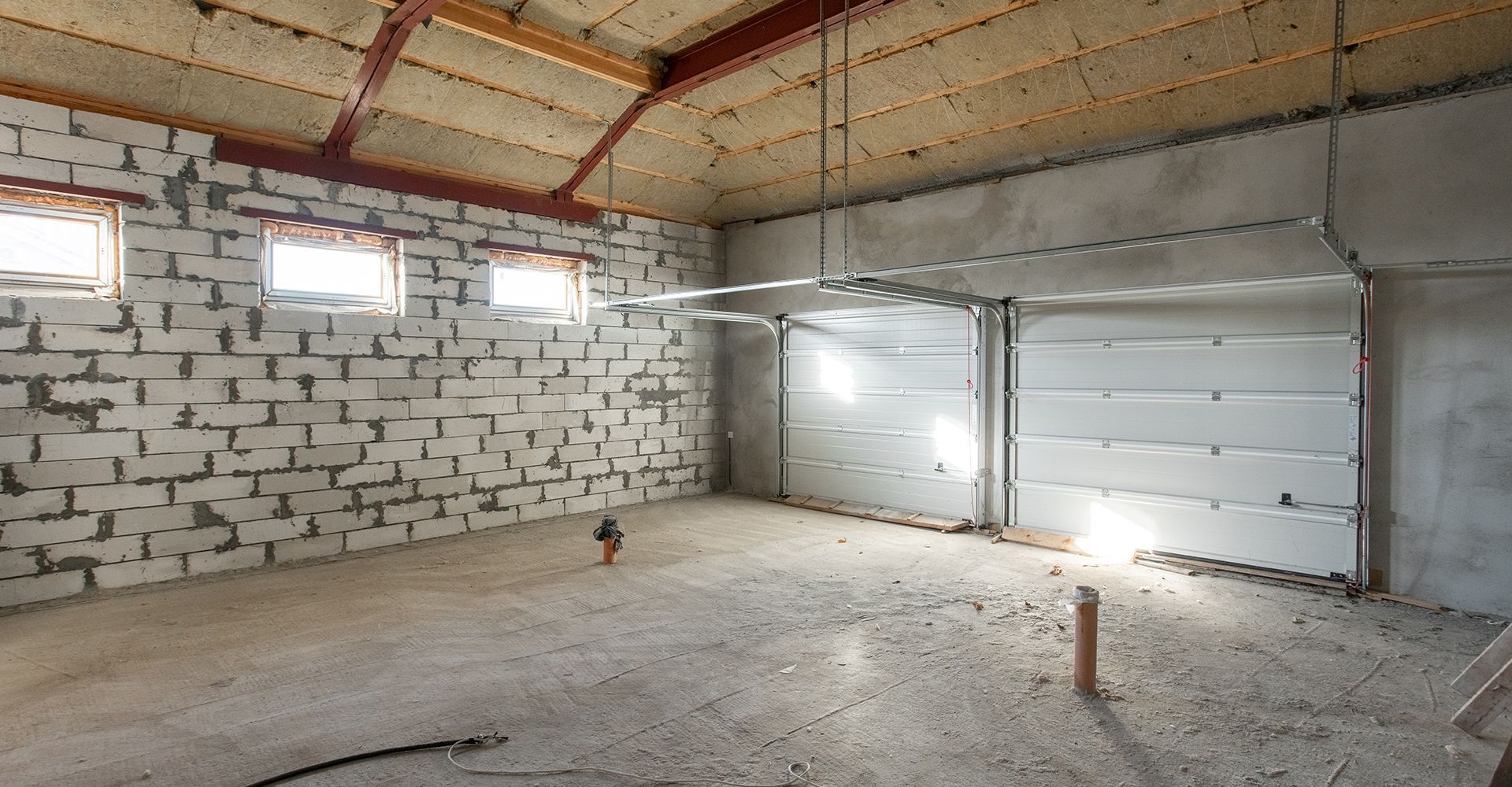 An empty garage with a brick wall and a garage door.