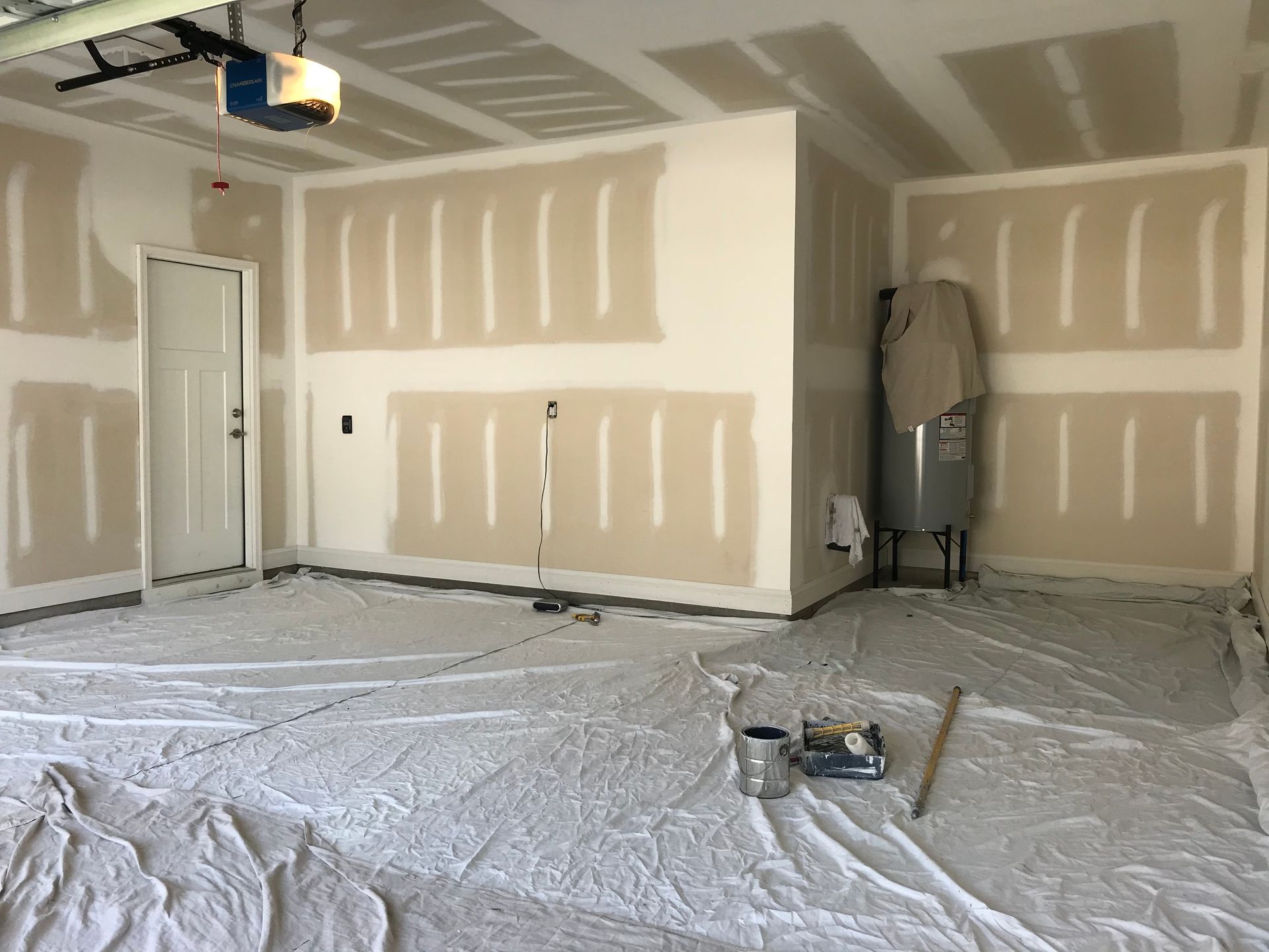 A garage is being painted with a white tarp on the floor.