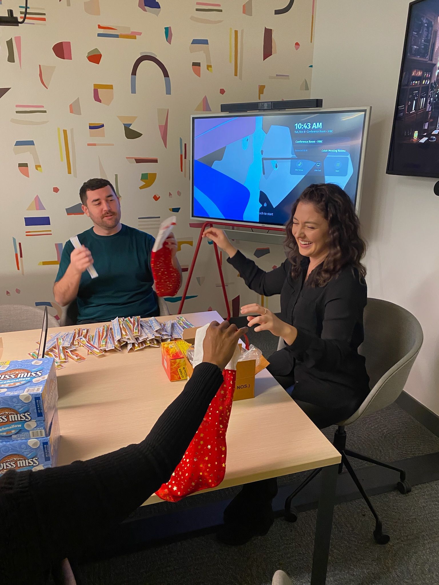 A group of people are sitting around a table in front of a television.
