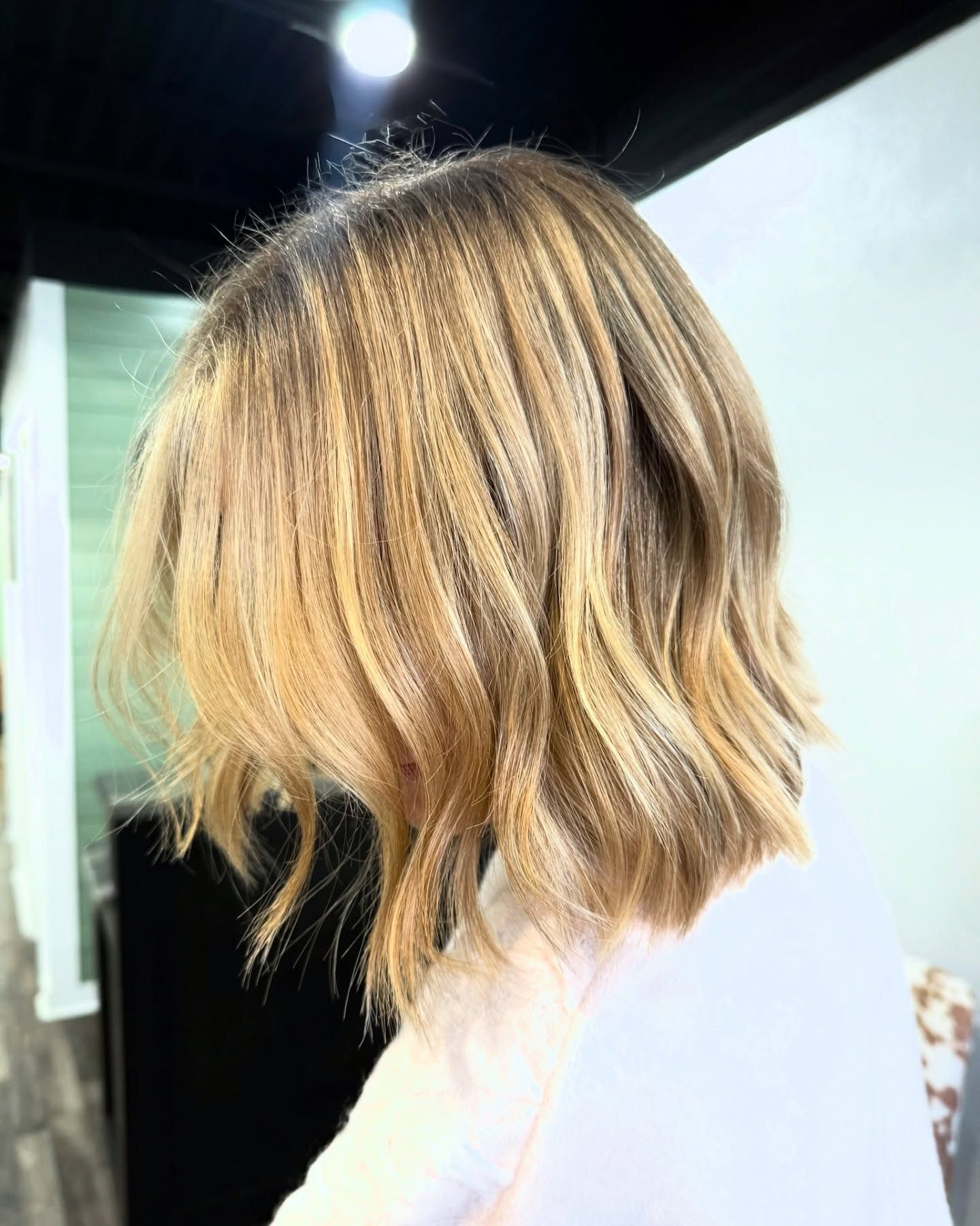 Blonde wavy bob haircut with highlights in a salon setting.