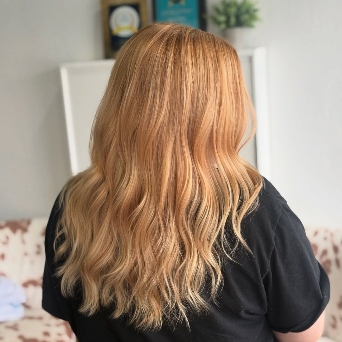Woman with long wavy light orange hair, wearing a black shirt, indoors.