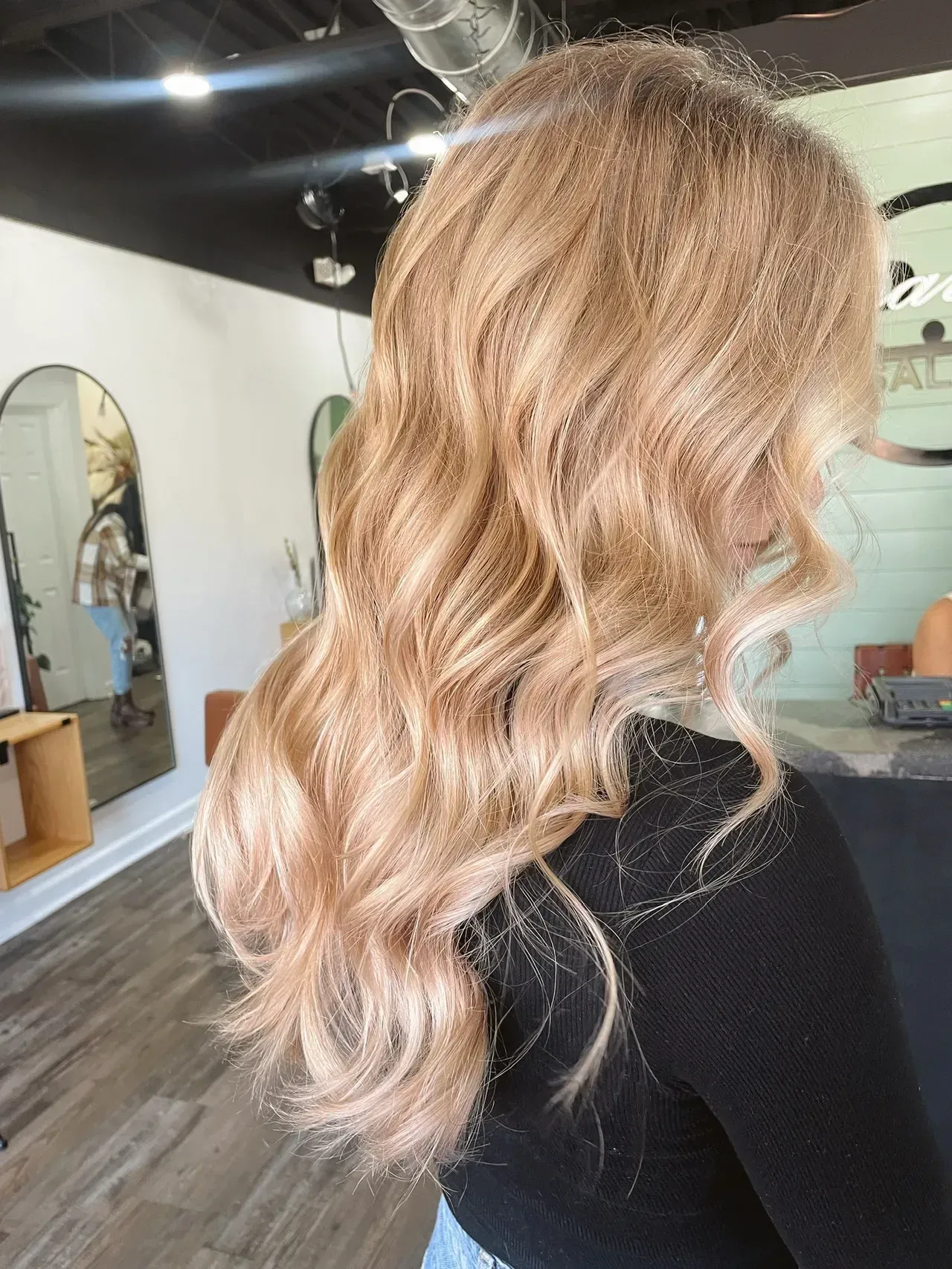 Woman with long, wavy blonde hair in a salon setting.