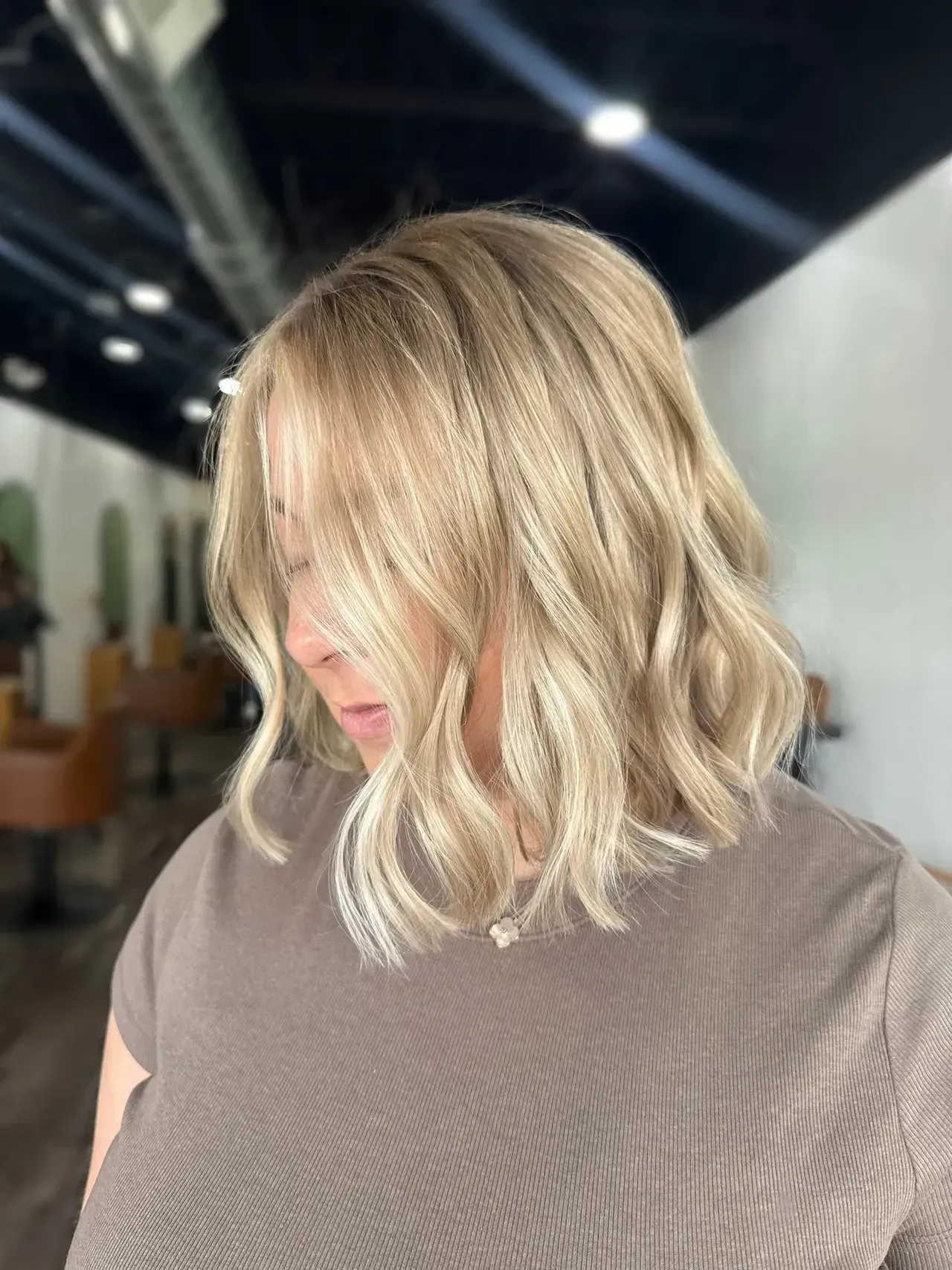 Blonde bob haircut with loose waves; woman in a salon.