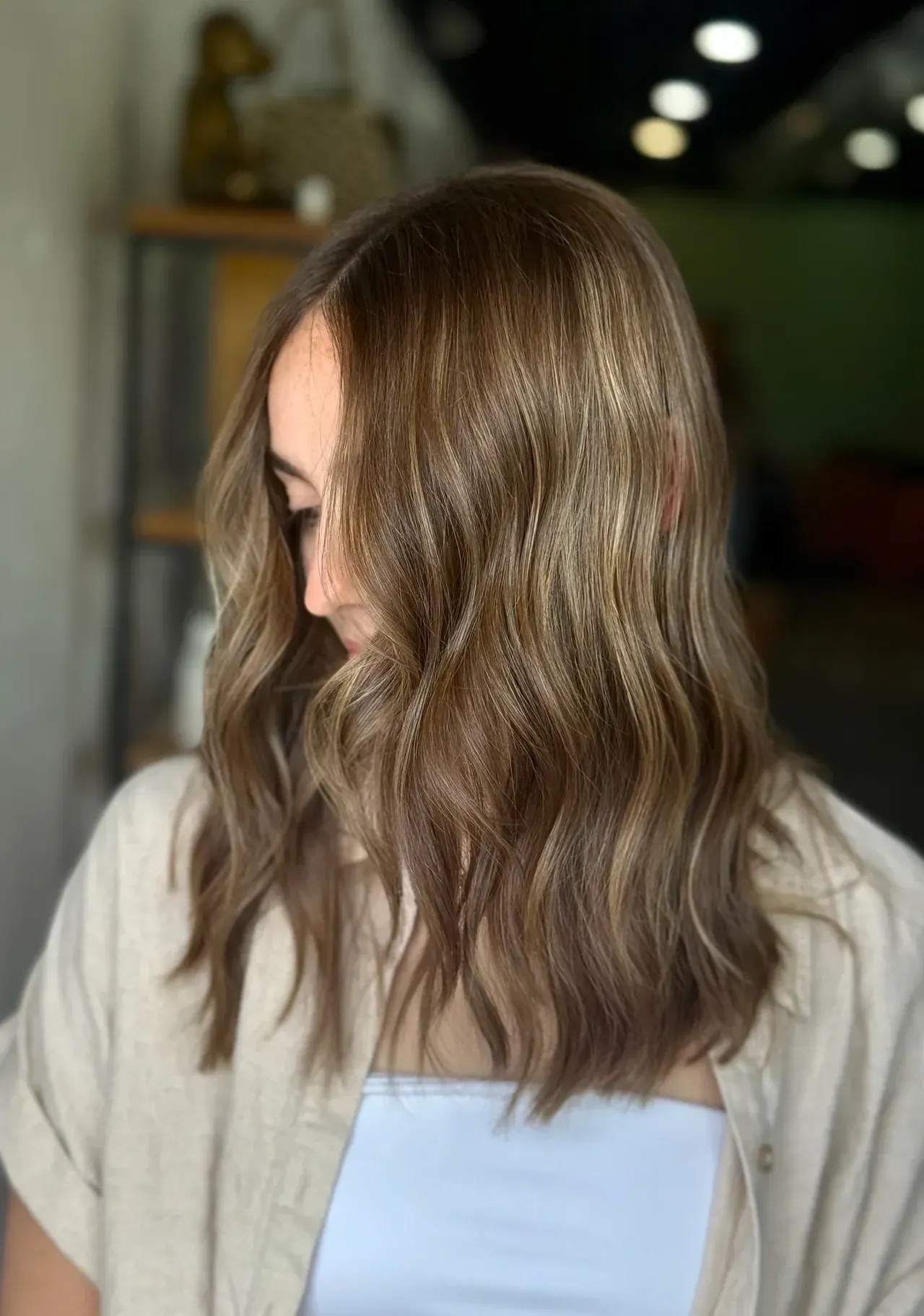 Woman with wavy brown and blonde highlighted hair; neutral-toned top.