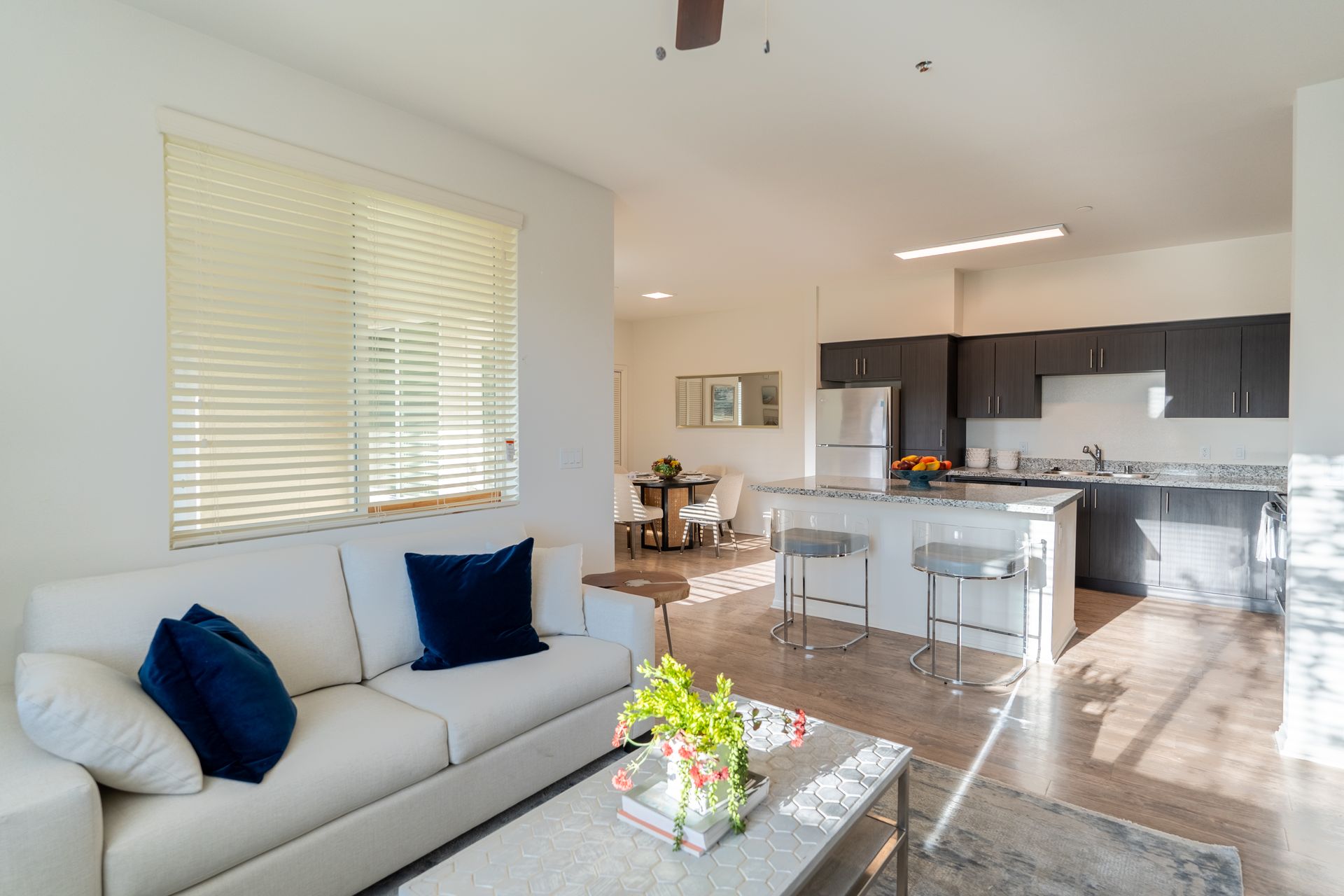 A living room with couch and television and angle viewing kitchen with island